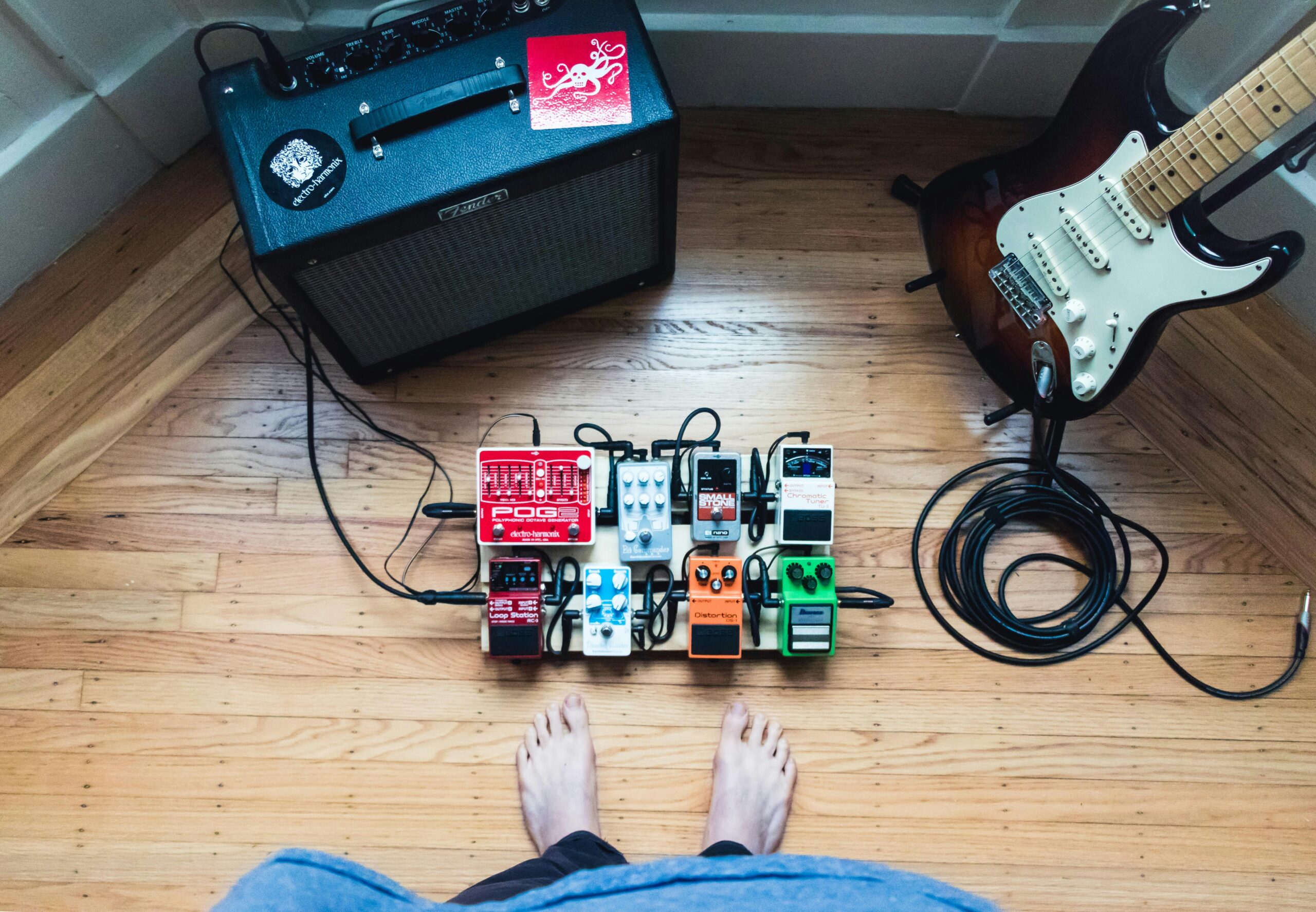 an electric guitar, pedal board, and amplifier